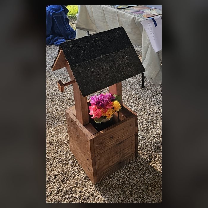 Handmade natural wood wishing well with a shingled roof and hanging bucket